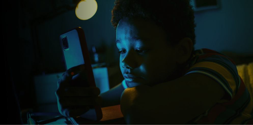 Pessoa utilizando o celular em um ambiente escuro